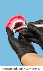 Head of high-speed dental handpiece with bur and a layout of the human jaw in dentist's hands. Dental instruments for dental treatment. Close-up view.