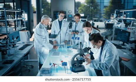 Head of Laboratory Making a Bioengineering Experiment with a Group of Young Science College Students. Future Specialists Working with Modern Microscopes, Using Tablet and Laptop Computers
