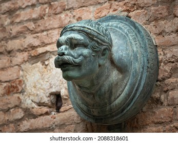 Head Of A Man With Big Moustache Made Of Bronze In Venice (Italy), Brick Wall, Outdoors On A Cloudy Day In Autumn