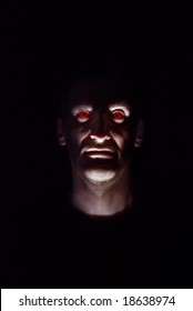 Head Of The Man With Red Eyes On A Black Background