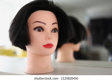 The head of a manikin with hair and makeup is standing near the mirror. Beauty salon with eyebrow permanent service