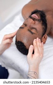 Head Massage In Spa Wellness Salon. Recovery Treatment. Wellness. Top View On Black Guy Client Lying On Couch Bed, Relaxing, With Eyes Closed. Above View. Healthy Lifestyle, Therapy