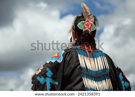Head of Native American woman in traditional costume against cloudy sky