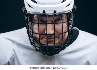 Head Portrait Of Grinning Hockey Goalie With Broken Tooth Wearing White Helmet Over Black Background