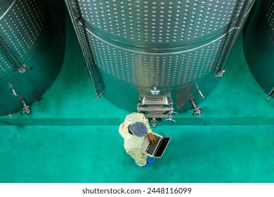 Head of quality control officer examines inside the food and beverage manufacturing factory. Female food scientist is checking a fermentation tank in the beverage factory. - Powered by Shutterstock