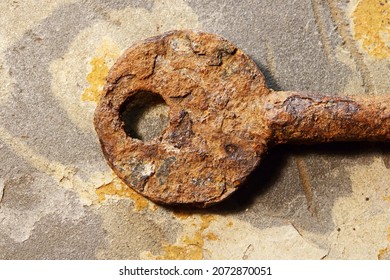 HEAD OF A SEVERELY RUST COATED KEY ON A PIECE OF SLATE