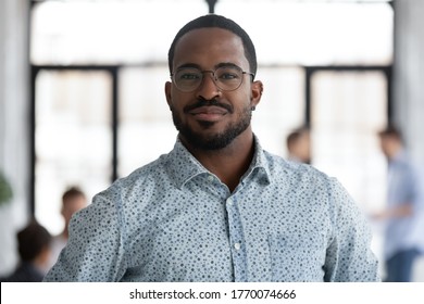 Head shot of african self-assured executive manager portrait, successful staff member company employee pose for camera photo shooting standing in office. Firm owner, proud founder, leadership concept