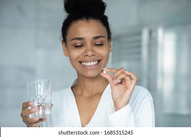 Head Shot African Woman Holds Pill And Glass Of Water. Taking Minerals For Female Skin And Health, Boost Metabolism, Vitamin A C Deficiency Prevention Treatment, Healthcare, Skincare Bodycare Concept