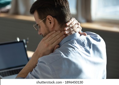 Head Shot Back Rear View Unhealthy Stressed Young Man Suffering From Painful Neck Feelings Due To Long Sedentary Computer Work At Home Office, Incorrect Posture, Chronic Inflammation Concept.