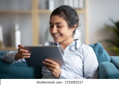 Head Shot Close Up Cheerful Young Indian Girl Holding Computer Tablet, Looking At Screen. Smiling Millennial Woman Watching Funny Video, Comedian Movie, Playing Entertaining Online Game At Home.