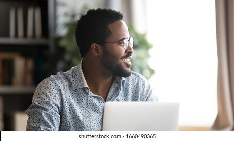 Head shot close up handsome happy young mixed race man distracted from job, looking aside at window. Smiling millennial businessman in eyewear dreaming visualizing future, planning weekend time.