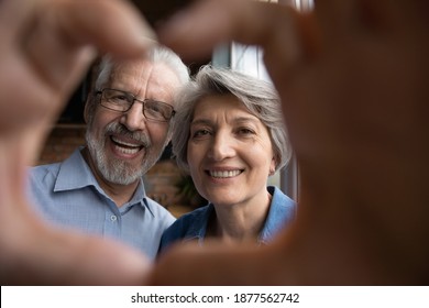 Head Shot Close Up Happy Bonding Older Senior Family Couple Making Heart Sign With Fingers, Showing Love And Care. Emotional Smiling Middle Aged Mature Spouses Enjoying Sweet Tender Moment Together.