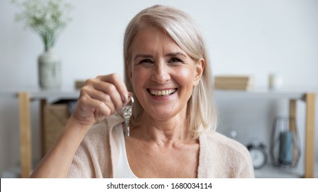 Head Shot Close Up Happy Middle Aged Woman Demonstrating Keys From New Apartment. Excited Older Lady Moving Into Own House. Satisfied Smiling Client Making Deal With Property Real Estate Purchase.