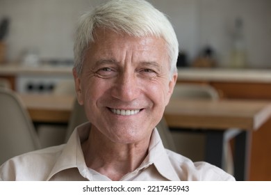 Head Shot Close Up Mature 60s Man Sits On Sofa Look At Camera, Having Wide Toothy Smile Feel Happy Enjoy Carefree Retired Life Relax Indoor. Medical Insurance For Older, Baby Boomer Person Portrait