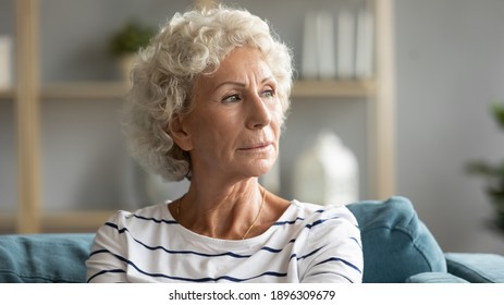 Head shot close up pensive old senior hoary woman looking in distance, recollecting memories or feeling lonely at home. Lost in thoughts middle aged grandmother relaxing on sofa, missing or mourning. - Powered by Shutterstock