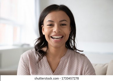 Head shot close up portrait African ethnicity woman sitting on couch takes part in videocall chatting with foreign friend webcam view, passes job interview distantly, blogger record new vlog concept