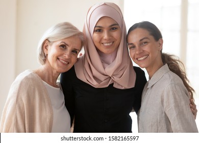 Head Shot Close Up Portrait Muslim Businesswoman In Hijab Embracing Happy Middle Aged And Young Mixed Race Colleagues. Multiracial Diverse Female Coworkers International Team Posing For Photo.