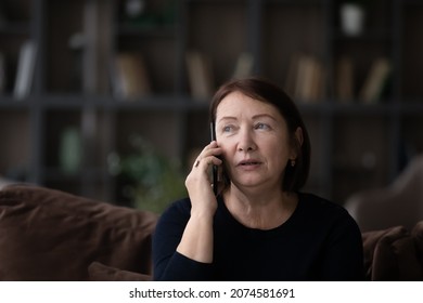 Head Shot Close Up Of Serious Mature Woman Talking On Phone At Home Sitting On Couch, Senior Female Holding Mobile Device Smartphone, Chatting With Relatives Or Friends, Making Or Answering Call