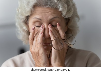 Head shot close up tired middle aged mature woman rubbing nose bridge after taking off eyewear. Frustrated stressed senior older grandmother suffering from blurred eyesight, eyes strain pain ache. - Powered by Shutterstock