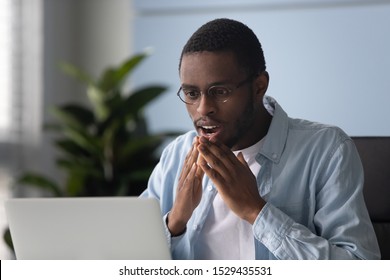 Head shot close up young african american male intern in eyeglasses surprised by received news at office. Astonished millennial mixed race worker reading unbelievable offer on computer at workplace. - Shutterstock ID 1529435531