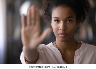 Head shot confident serious strong millennial generation african ethnicity woman looking at camera showing stop sign, denying abuse or bullying, protesting against racial or gender discrimination.