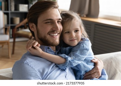 Head Shot Cute Small Baby Girl Cuddling Neck Of Smiling Young Father, Enjoying Calm Sweet Tender Moment Together Relaxing On Sofa, Watching TV Series Or Cartoons In Living Room, Holiday Pastime.