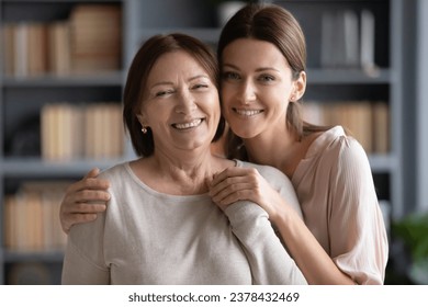 Head shot different generation relatives women standing in living room looking at camera, adult daughter hugs old mother, concept of love, protection, warm relations between grown up child and parent - Powered by Shutterstock