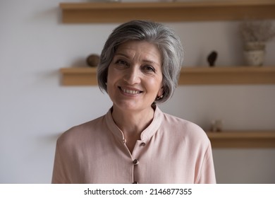 Head shot of good-looking elegant middle-aged woman having charming smile posing standing alone indoor staring at camera. Professional tutor portrait, medical insurance cover for older citizen concept