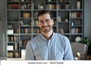 Head shot handsome millennial 30s professional employee worker posing for camera at modern office. Business portrait, creative occupation person. Teacher, experienced business coach indoors concept