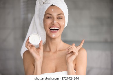 Head Shot Happy 30s Woman With Towel On Head Holds Night Or Day Cream Jar Anti-ageing Beauty Treatment Advertises Effective Product, Moisturizing And Hydration, Deep Regeneration Facial Creme Concept