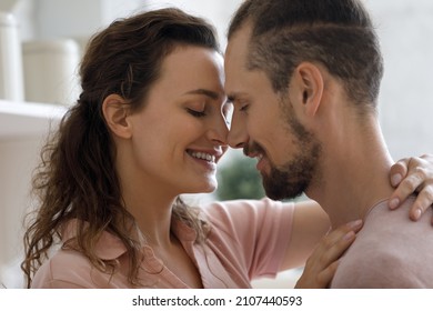 Head shot happy affectionate young married family couple cuddling, touching noses, showing sincere loving tender feelings, enjoying romantic home dating time together, candid relations concept.