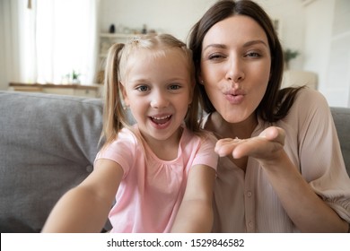 Head Shot Happy Little Daughter And Mother Taking Selfie, Sending Blow Kiss Close Up, Having Fun, Loving Smiling Mum And Adorable Preschool Child Looking At Camera, Enjoying Free Time Together