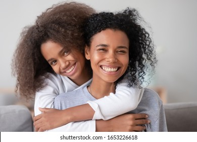 Head Shot Of Happy Loving African American Family Single Mother And Teen Girl Embracing Mom From Behind Looking At Camera, Smiling Black Mum And Mixed Race Teenage Daughter Hugging Laughing, Portrait