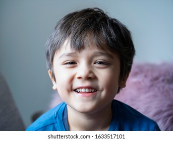 Head shot of healthy kid, Portrait happy child looking at camera with smiling face, candid shot cute little boy relaxing stay at home during covid lock down.Positive children concept,Social distancing