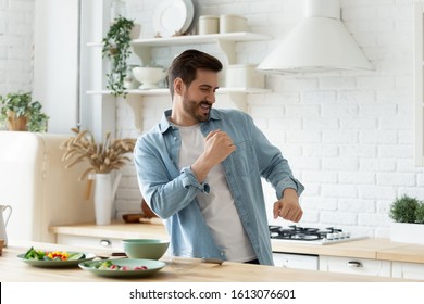 Head Shot Joyful Young Man Dancing At Modern Kitchen On Weekend Morning, Preparing Healthy Food. Carefree Handsome Guy Enjoying Leisure Time, Moving At Music, Cooking Breakfast Alone At Home.