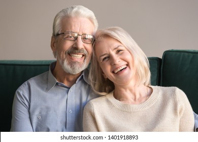 Head Shot Laughing Retirees Pretty Couple Sitting On Couch At Home, Spouses Having Candid Healthy Toothy Smile, Dental Treatment Check-up Services For Old People, Medical Insurance Health Care Concept