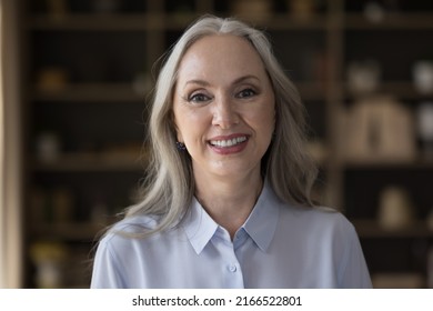 Head shot of middle-aged attractive businesswoman standing in office posing for cam, having wide candid toothy smile staring at camera feels happy. Portrait of baby boomer generation female concept - Powered by Shutterstock