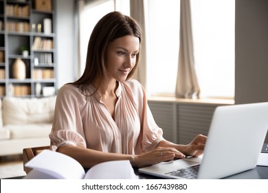 Head shot pleasant happy young woman freelancer working on computer at home. Attractive businesswoman studying online, using laptop software, web surfing information or shopping in internet store. - Shutterstock ID 1667439880