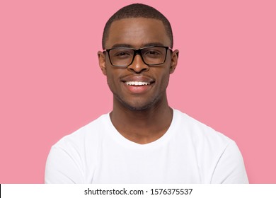 Head Shot Portrait African American Man In Glasses Looking At Camera, Satisfied Male With Healthy Toothy Smile, Satisfied Teenage Student In White T-shirt, Isolated On Pink Studio Background