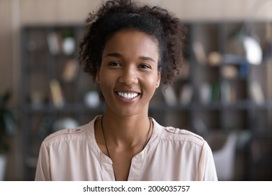 Head shot portrait of African American attractive woman looking at camera, close up happy beautiful young female with healthy toothy smile and perfect smooth skin posing for photo, profile picture