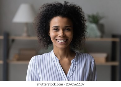 Head shot portrait of attractive African American woman, beautiful young female with healthy toothy smile and perfect skin looking at camera, happy homeowner tenant posing for profile picture at home - Powered by Shutterstock