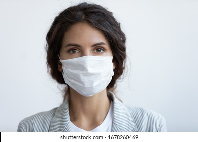 Head shot portrait attractive woman looking at camera wear medical or surgical blue colour face mask protecting from COVID19 or corona virus. Personal care during pandemic infectious disease outbreak