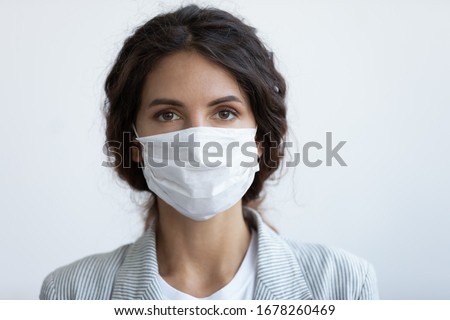 Head shot portrait attractive woman looking at camera wear medical or surgical blue colour face mask protecting from COVID19 or corona virus. Personal care during pandemic infectious disease outbreak