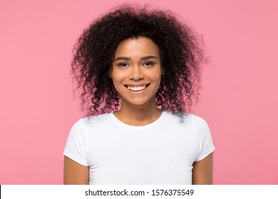 Head shot portrait beautiful African American woman with healthy beaming smile looking at camera, young attractive female with curly hair wearing white t-shirt, isolated on pink studio background - Powered by Shutterstock