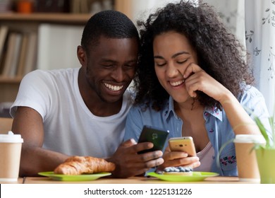 Head shot portrait black guy and biracial girl couple in love sitting together at table in cafe drink coffee eat pastries. Couple using cellular sharing videos having fun. Wireless technology concept - Powered by Shutterstock