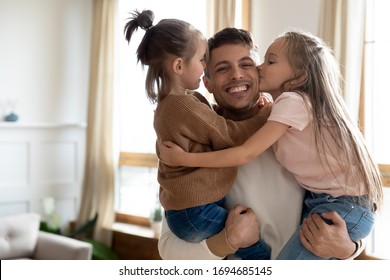 Head shot portrait of cheerful daddy holding adorable little children siblings, looking at camera. Cute small kids sisters kissing cuddling young excited father, enjoying weekend tender time together. - Shutterstock ID 1694685145