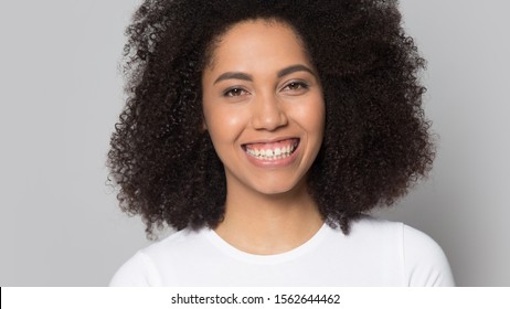 Head shot portrait close up excited beautiful African American girl with wide toothy smile, having fun, pretty young female with curly hair looking at camera, isolated on grey studio background
