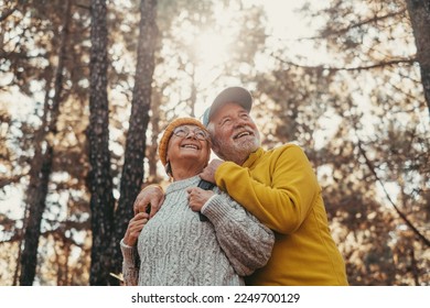 Head shot portrait close up of middle age cheerful people smiling and looking at the the trees of the forest around them. Active couple of old seniors hiking and walking together in the mountain - Powered by Shutterstock