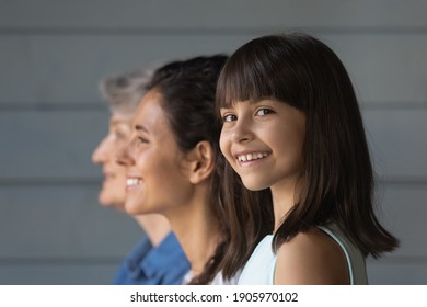 Head shot portrait close up smiling little girl with young mother and mature grandmother standing on grey wooden wall background in row, three generations of women concept, family unity and bonding - Powered by Shutterstock