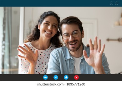 Head shot portrait computer screen view happy young couple waving hands, looking at camera, smiling wife and husband greeting friends or relatives, talking, chatting online, using webcam at home - Powered by Shutterstock